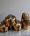 Set of gold kitchenware items on a marble surface with a neutral background