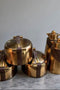Set of gold kitchenware items on a marble surface with a neutral background