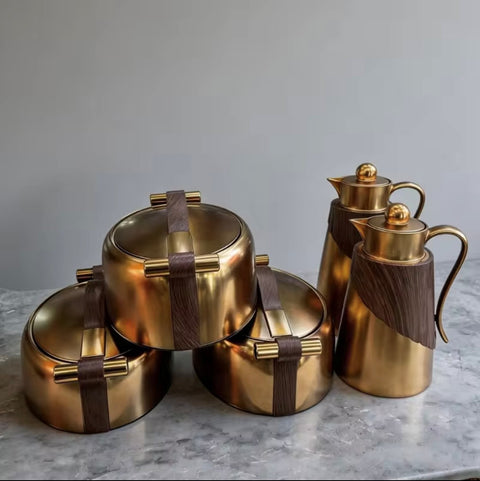 Set of gold kitchenware items on a marble surface with a neutral background