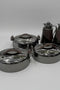 Set of metallic containers with lids on a white tiled floor