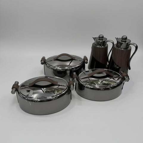 Set of metallic containers with lids on a white tiled floor